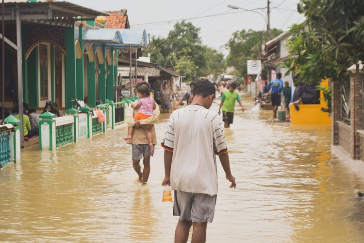 Hujan lebat yang mengguyur daerah Bone Bolango selama beberapa hari terakhir telah mengakibatkan bencana alam yang cukup mengkhawatirkan. Banjir yang melanda sembilan desa di dua kecamatan ini menimbulkan dampak yang signifikan bagi masyarakat setempat. Peristiwa ini tidak hanya merusak infrastruktur, tetapi juga mengancam keselamatan warga, menyebabkan kerugian material, dan mengganggu aktivitas sehari-hari. Artikel ini akan membahas secara mendetail tentang penyebab, dampak, penanganan, dan upaya mitigasi yang dilakukan untuk menghadapi bencana banjir ini. 1. Penyebab Hujan Lebat dan Banjir di Bone Bolango Hujan lebat yang terjadi di Bone Bolango dapat diatribusikan kepada beberapa faktor. Salah satunya adalah kondisi cuaca yang ekstrem, di mana perubahan iklim telah menyebabkan pola hujan yang tidak menentu. Musim hujan yang seharusnya berlangsung pada waktu tertentu kini sering kali datang lebih awal atau lebih lambat. Selain itu, fenomena alam seperti El Niño dan La Niña juga berkontribusi pada peningkatan intensitas hujan di beberapa daerah. Faktor geografis juga berperan dalam terjadinya banjir. Daerah Bone Bolango yang terletak di dataran rendah dan dikelilingi oleh pegunungan sering kali menjadi tempat aliran air hujan. Saat curah hujan meningkat, sungai-sungai dapat meluap dan menggenangi pemukiman di sekitarnya. Selain itu, masalah penggundulan hutan dan konversi lahan menjadi pemukiman atau lahan pertanian juga memperburuk kondisi ini. Tanpa vegetasi yang cukup untuk menyerap air hujan, tanah menjadi lebih rentan terhadap erosi dan banjir. Terakhir, sistem drainase yang kurang memadai juga menjadi salah satu penyebab utama terjadinya banjir. Banyak desa di Bone Bolango tidak memiliki saluran drainase yang baik, sehingga air hujan tidak dapat mengalir dengan lancar. Hal ini menyebabkan genangan air yang berpotensi menjadi banjir, terutama saat hujan lebat. Semua faktor ini saling berinteraksi dan memperburuk kondisi, menyebabkan banjir yang melanda sembilan desa di dua kecamatan. 2. Dampak Banjir terhadap Masyarakat dan Infrastruktur Dampak banjir yang melanda Bone Bolango sangatlah luas dan beragam. Pertama, dari segi masyarakat, banyak warga yang kehilangan tempat tinggal dan harta benda akibat terendam air. Hujan yang terus menerus mengakibatkan permukiman terendam, dan banyak keluarga terpaksa mengungsi ke tempat yang lebih aman. Kehilangan harta benda seperti perabot rumah, kendaraan, dan dokumen penting sangat mempengaruhi kehidupan sehari-hari mereka. Selain itu, banjir juga mengganggu akses terhadap layanan kesehatan, pendidikan, dan layanan publik lainnya. Dari segi infrastruktur, banjir mengakibatkan kerusakan jalan, jembatan, dan fasilitas umum lainnya. Jalan yang terendam membuat mobilitas masyarakat menjadi sangat terganggu, dan banyak warga yang terisolasi. Kerusakan jembatan berpotensi memperlambat distribusi bantuan kemanusiaan dan memperburuk keadaan. Di sisi lain, fasilitas umum seperti sekolah dan puskesmas juga tidak luput dari dampak, sehingga kegiatan belajar mengajar terpaksa dihentikan dan pelayanan kesehatan terganggu. Dampak jangka panjang dari banjir ini juga patut diperhatikan. Banyak warga yang kehilangan mata pencaharian, terutama mereka yang bergantung pada pertanian dan perdagangan. Saat lahan pertanian terendam, hasil panen menjadi gagal dan pendapatan masyarakat menurun drastis. Selain itu, psikologis masyarakat juga terganggu akibat trauma yang ditimbulkan oleh bencana ini. Hal ini menyiratkan perlunya penanganan yang komprehensif untuk membantu masyarakat pulih dari bencana ini. 3. Penanganan dan Respons Terhadap Banjir Ketika banjir melanda, respons cepat dari pemerintah dan organisasi kemanusiaan sangat dibutuhkan. Pemerintah daerah Bone Bolango bersama dengan Badan Penanggulangan Bencana Daerah (BPBD) segera mengambil langkah untuk menangani situasi darurat. Tim penyelamat dikerahkan untuk mengevakuasi warga yang terjebak di daerah terdampak. Selain itu, posko pengungsian didirikan untuk menampung warga yang kehilangan tempat tinggal. Penyediaan bantuan juga menjadi fokus utama dalam penanganan bencana ini. Sembako, air bersih, dan obat-obatan didistribusikan kepada warga yang terdampak. Selain itu, upaya pemulihan infrastruktur juga dilakukan secepat mungkin agar akses menuju daerah terdampak kembali normal. Kerja sama lintas sektoral antara instansi pemerintah, TNI, Polri, dan masyarakat sangat penting untuk mempercepat proses penanganan. Namun, penanganan banjir tidak hanya dilakukan saat bencana terjadi. Upaya mitigasi juga penting untuk mencegah terulangnya bencana serupa di masa depan. Pemerintah daerah perlu melakukan perbaikan sistem drainase, reboisasi, dan pengaturan penggunaan lahan agar dapat mengurangi risiko banjir. Edukasi kepada masyarakat tentang cara mitigasi bencana juga perlu digalakkan agar mereka lebih siap menghadapi kemungkinan bencana di masa depan. 4. Upaya Mitigasi dan Kesadaran Masyarakat Upaya mitigasi banjir di Bone Bolango harus dilakukan secara berkelanjutan. Salah satu langkah yang dapat diambil adalah perbaikan dan pembangunan infrastruktur drainase yang lebih baik. Pembangunan saluran drainase yang memadai dapat membantu mengalirkan air hujan dengan lebih efektif, sehingga mengurangi risiko banjir. Selain itu, pembangunan waduk atau kolam retensi juga dapat menjadi solusi untuk menampung air hujan yang berlebihan. Reboisasi menjadi langkah penting dalam mitigasi bencana ini. Penanaman pohon di daerah hulu sungai dapat meningkatkan kemampuan tanah dalam menyerap air hujan dan mencegah erosi. Selain itu, pengurangan konversi lahan pertanian atau hutan menjadi pemukiman juga perlu diperhatikan agar tidak merusak ekosistem yang ada. Kesadaran masyarakat juga sangat penting dalam upaya mitigasi. Edukasi tentang pengelolaan limbah dan penggunaan lahan yang bijak dapat membantu masyarakat mengurangi risiko banjir. Mereka perlu dilibatkan dalam program-program mitigasi yang diadakan oleh pemerintah, sehingga mereka merasa memiliki tanggung jawab untuk menjaga lingkungan dan mengurangi dampak bencana di daerah mereka.